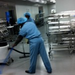 Two uniformed cleaners mopping and cleaning a medical equipment cleaning room